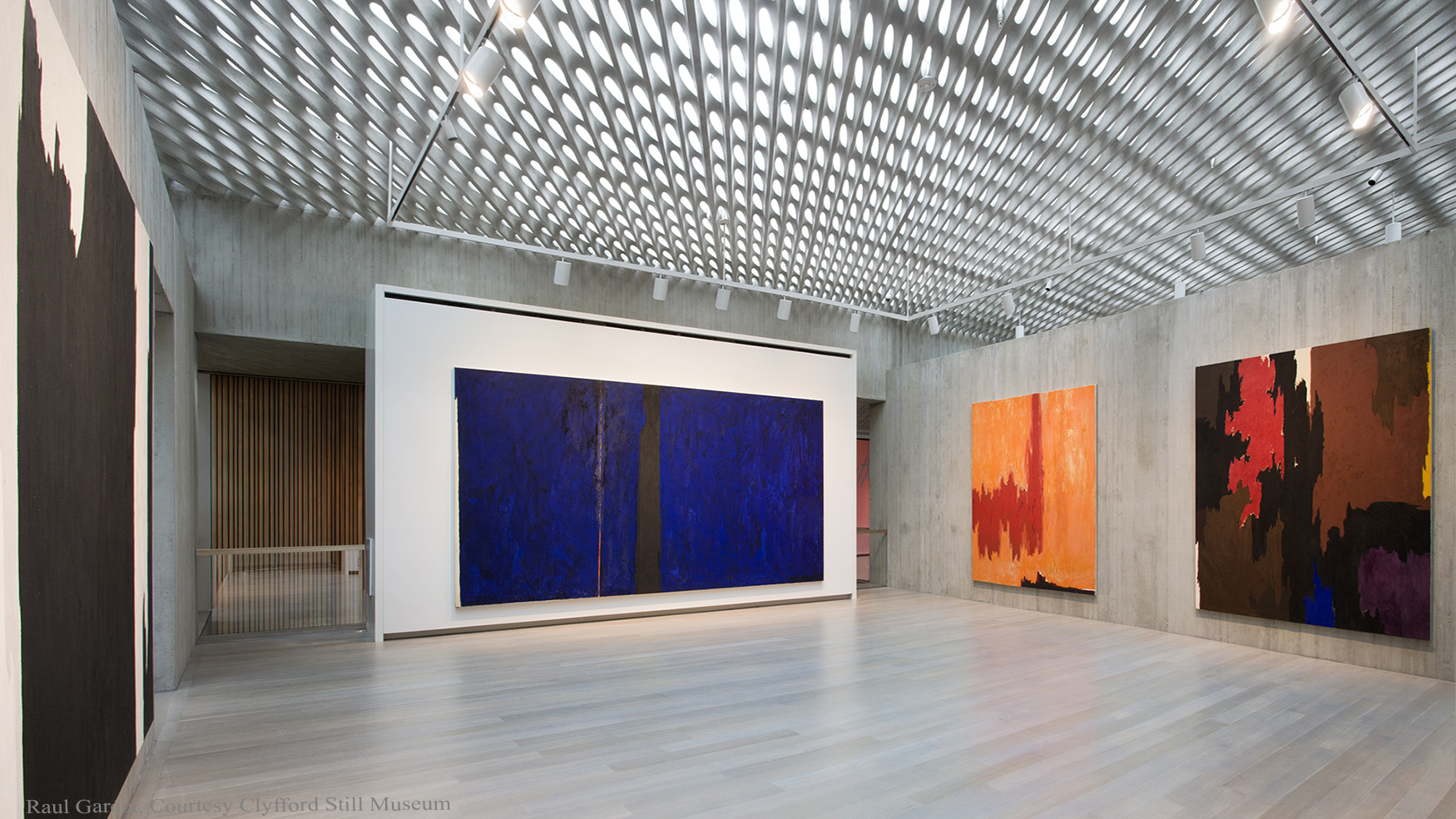 Gallery inside the Clyfford Still Museum with large abstract paintings on the wall and the ceiling visible