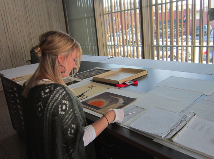 Conservator wearing white gloves works on artwork and papers