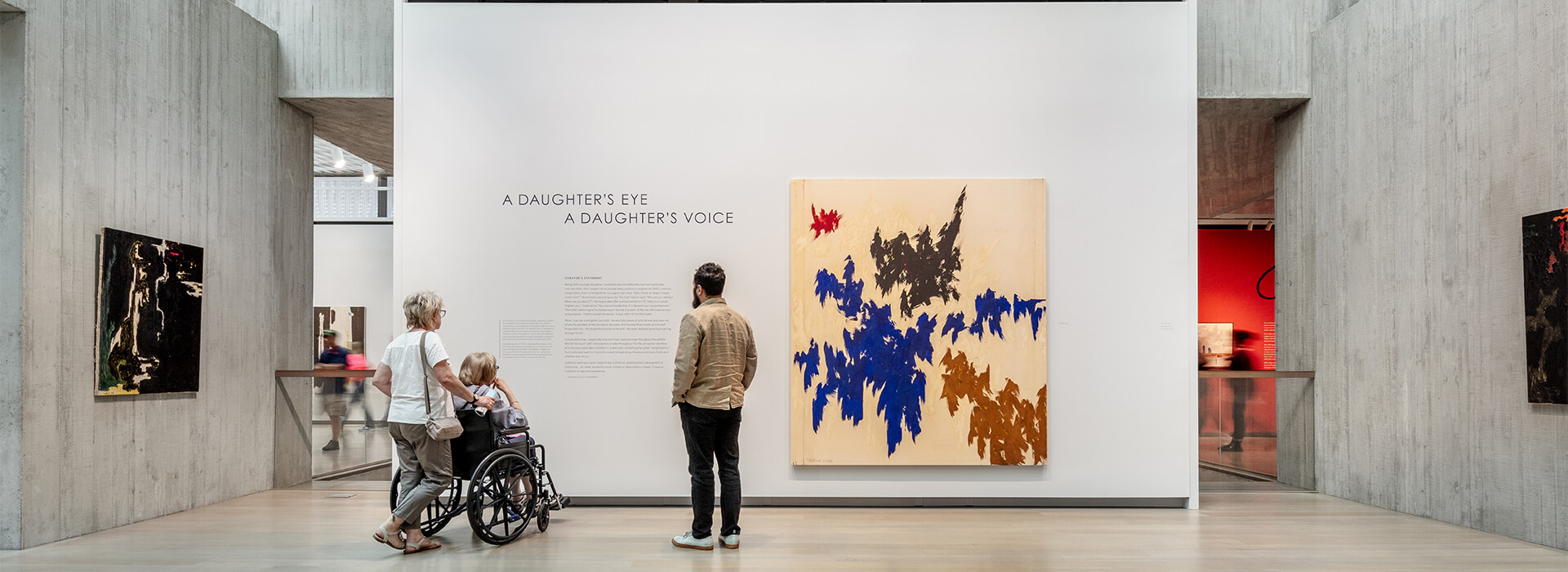 Guests at the Clyfford Still Museum look at text on the wall next to a painting