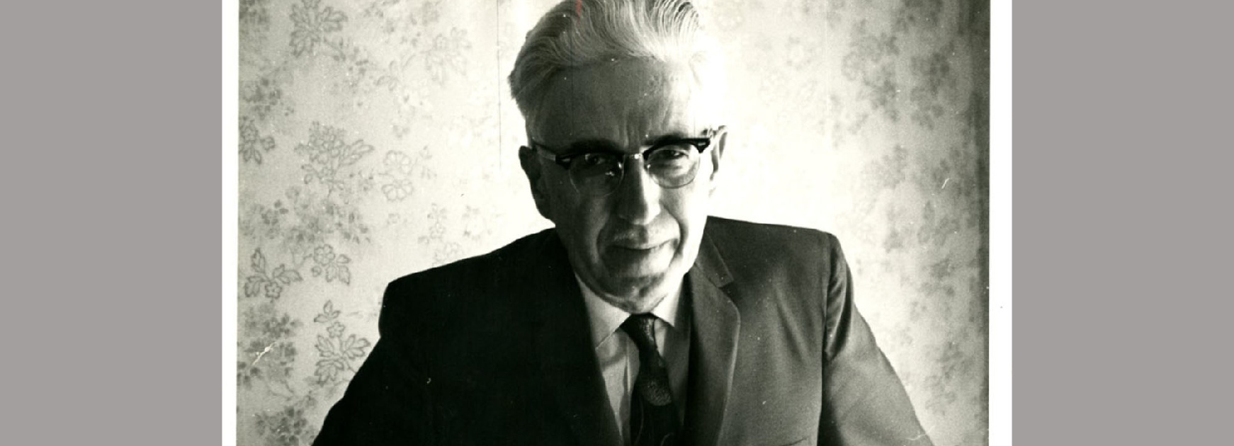 Black and white portrait of Clyfford Still wearing a suit and tie and glasses