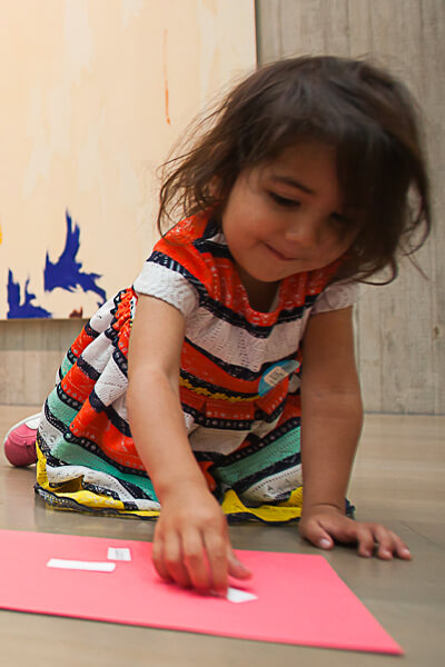 Young girl sit on the floor of an art gallery and puts words on a piece of paper