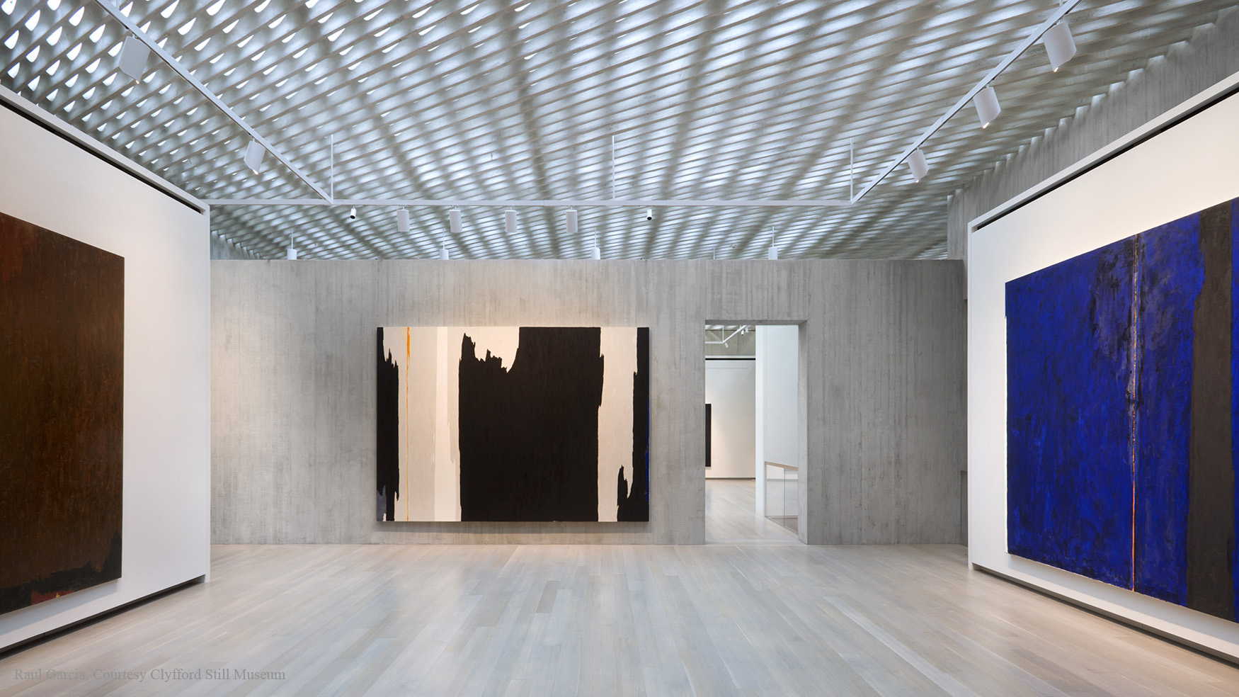 Gallery inside the Clyfford Still Museum with large abstract paintings on the wall and the ceiling visible