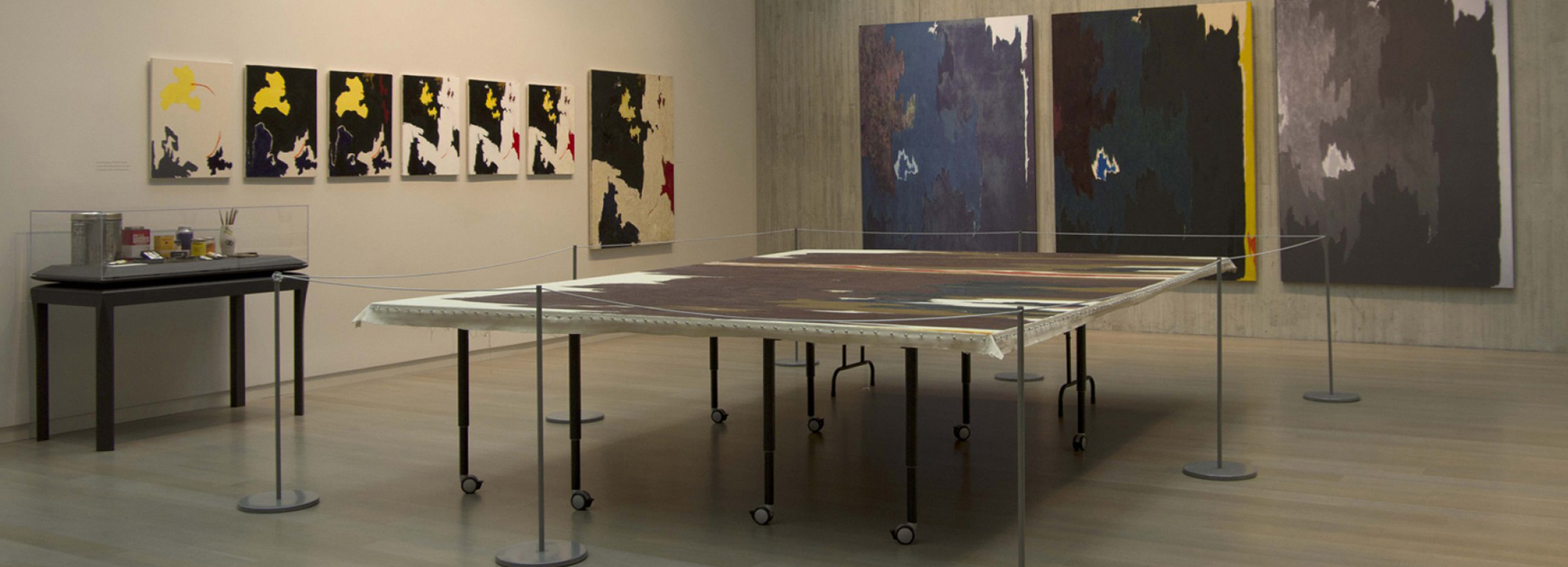 Photo of a gallery in the Clyfford Still Museum with artworks on the wall and a painting displayed on a table in the center of the room