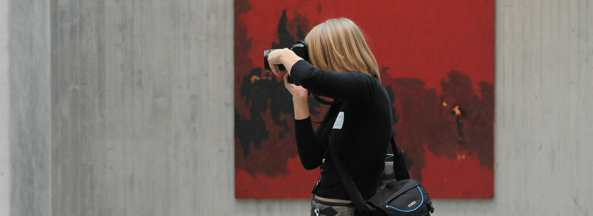 Woman takes a photo in front of a red painting
