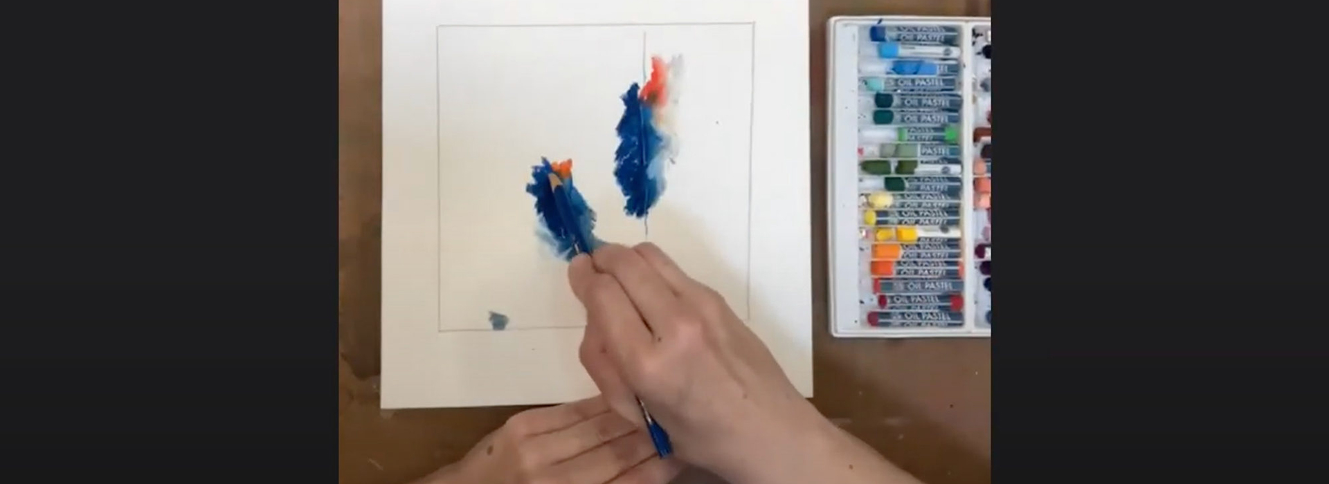 Looking down at a woman's hands on a screen as she draws with colored pencil and pastels