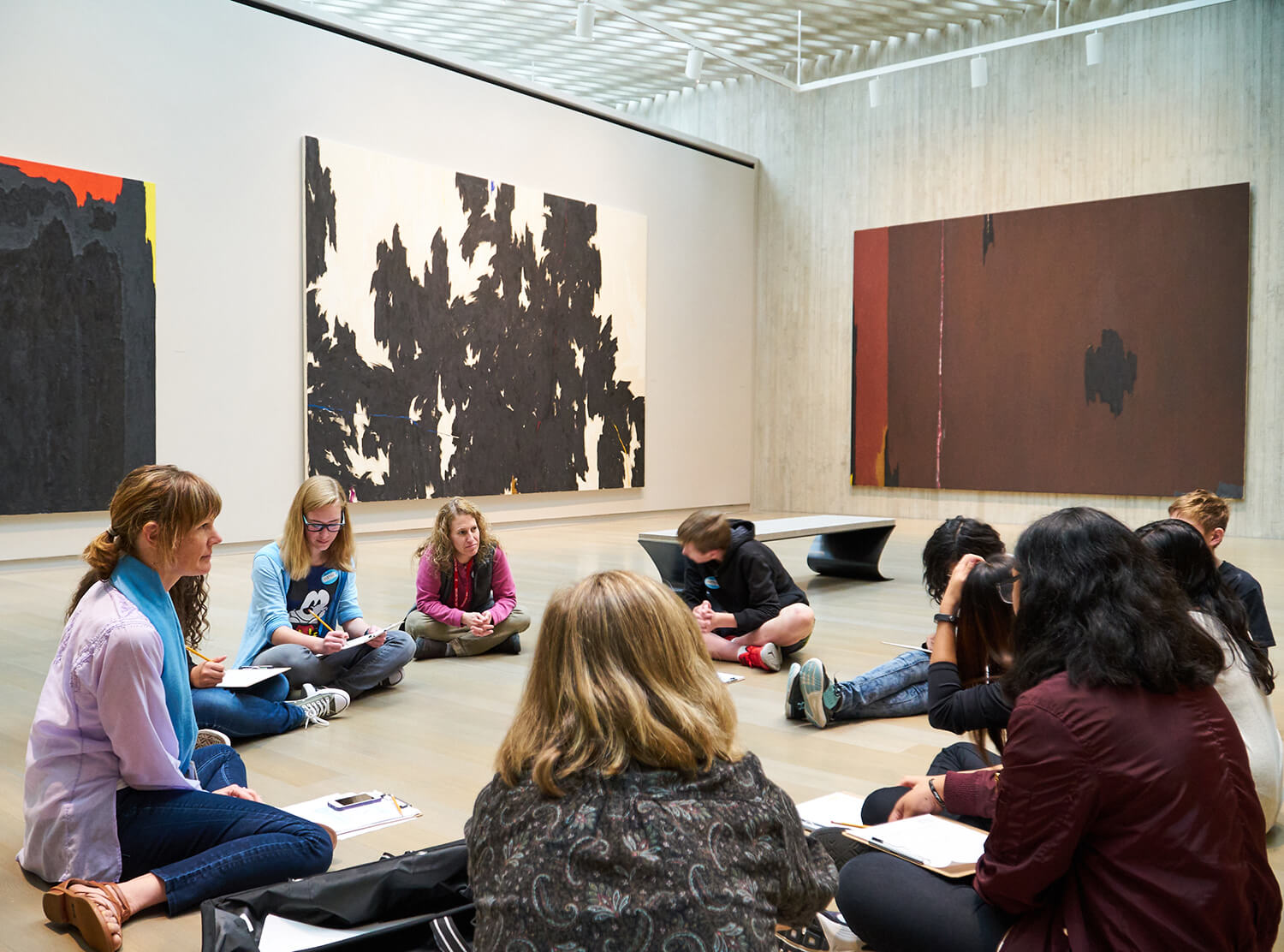 Students and teachers sit on the floor of a gallery at the Clyfford Still Museum