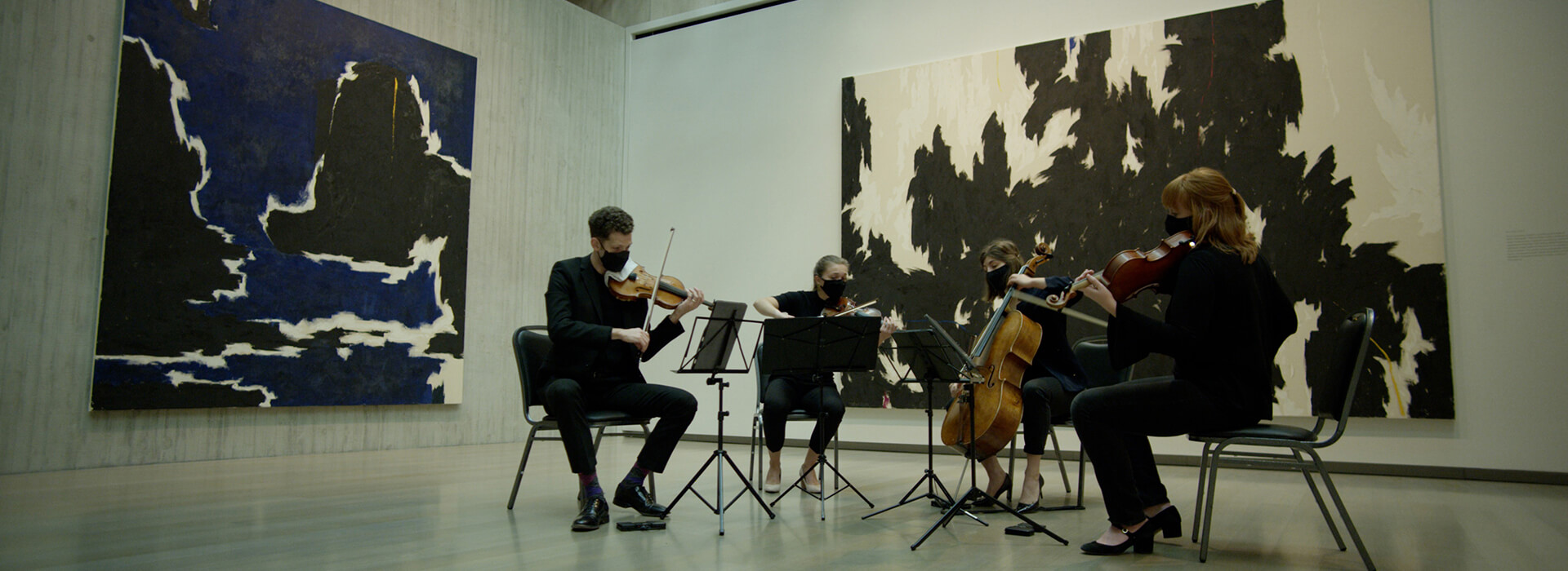 String quartet plays in front of a large black and white abstract painting