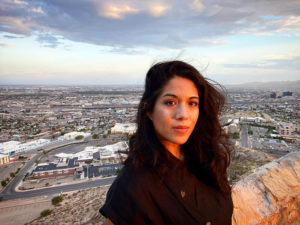 Woman looks at the camera with a cityscape behind her