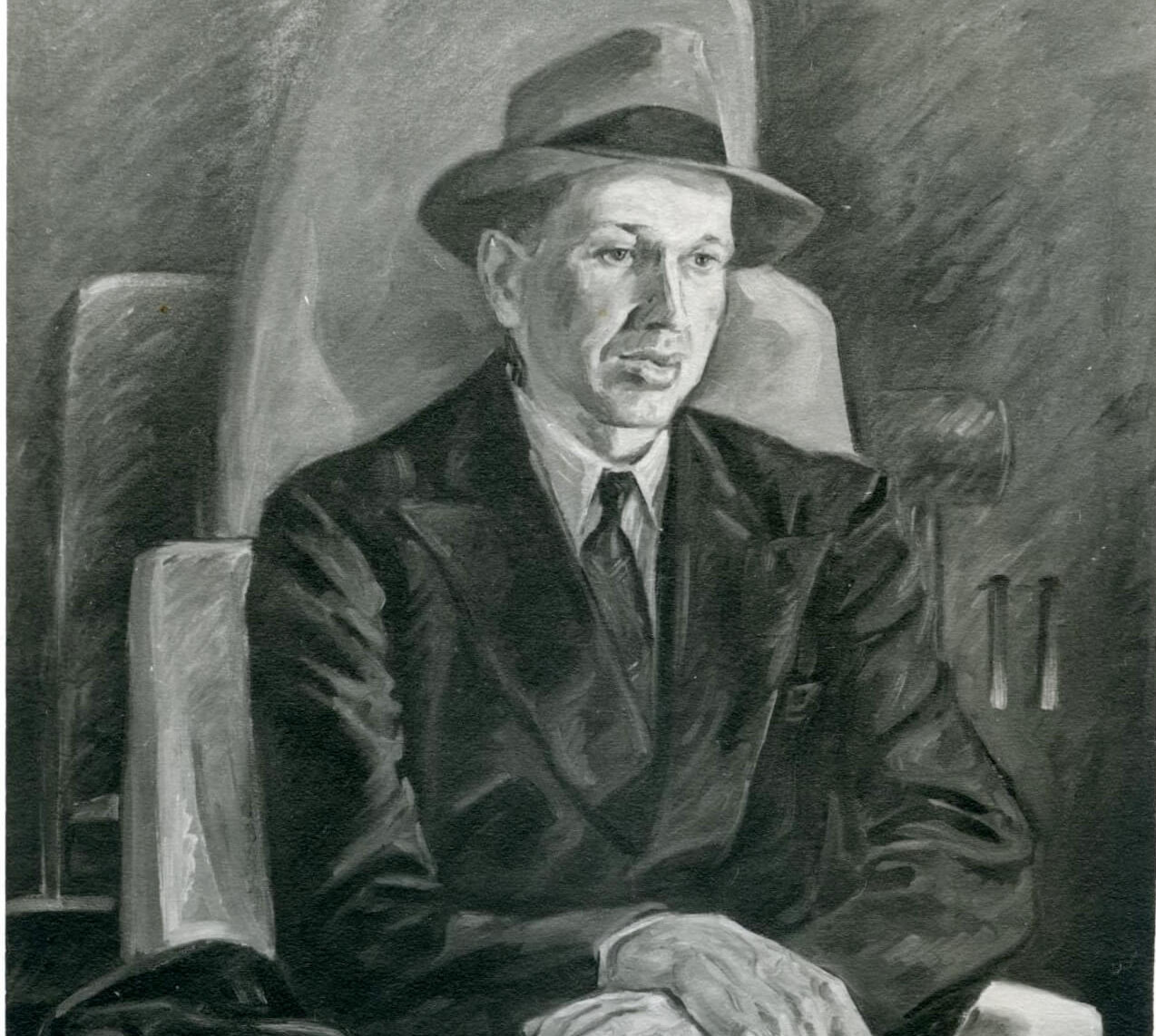 Portrait of a man sitting with his arms crossed across his knee wearing a suit and hat