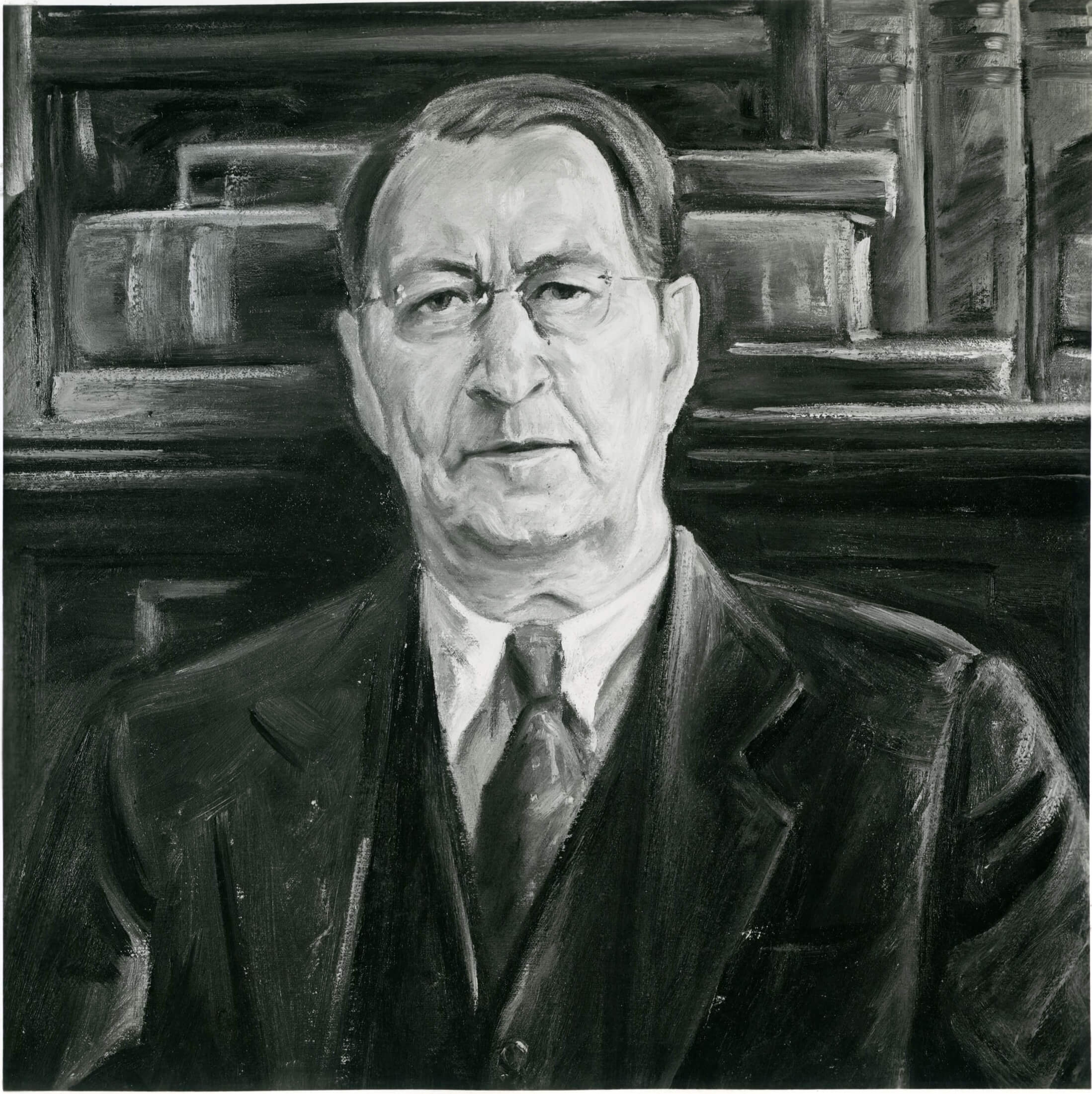 Portrait of a man wearing a suit and tie with books behind him