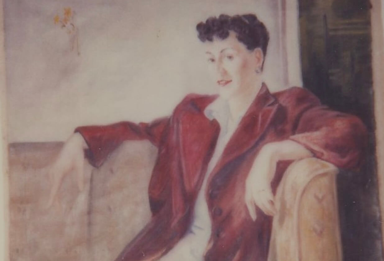 Portrait of a woman sitting in a chair with her arms up on the armrests wearing a red jacket