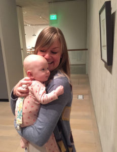 Woman holds baby who looks at art on the wall in a museum