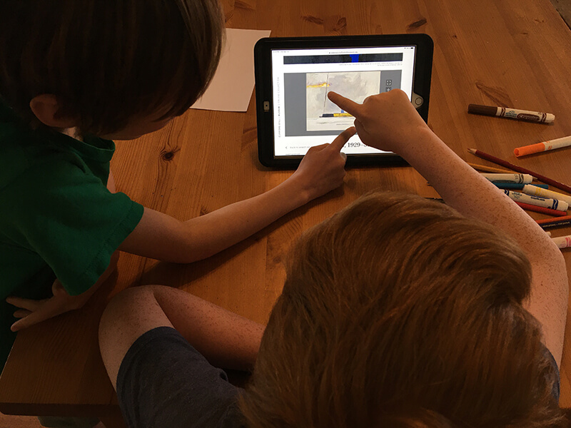 Two children point at an artwork on a tablet screen