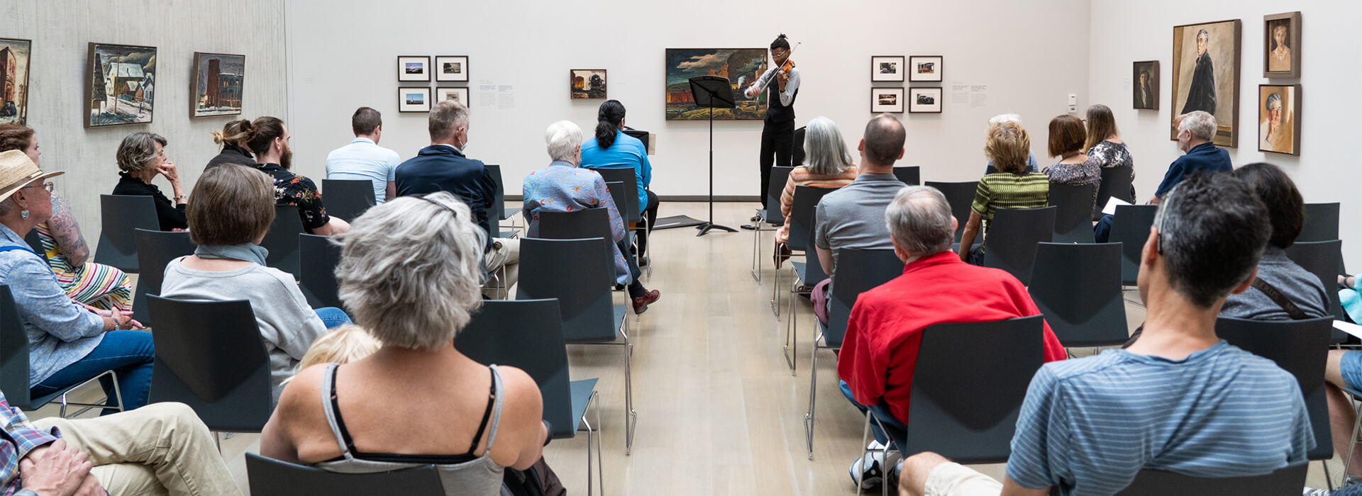 People sit and listen to chamber music in an art gallery