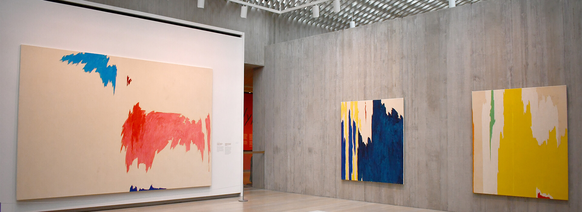 An art gallery with concrete walls and large colorful abstract artworks