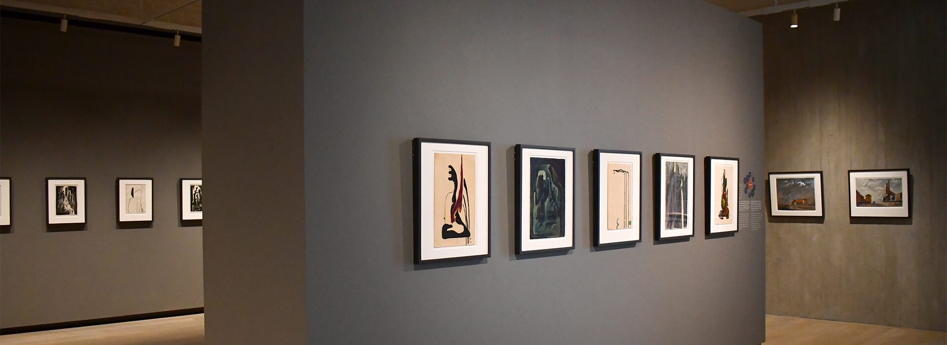 Image of gallery with gray walls and small framed artworks on paper