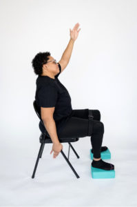Brittany Murdock sitting in a chair with yoga blocks under her feet