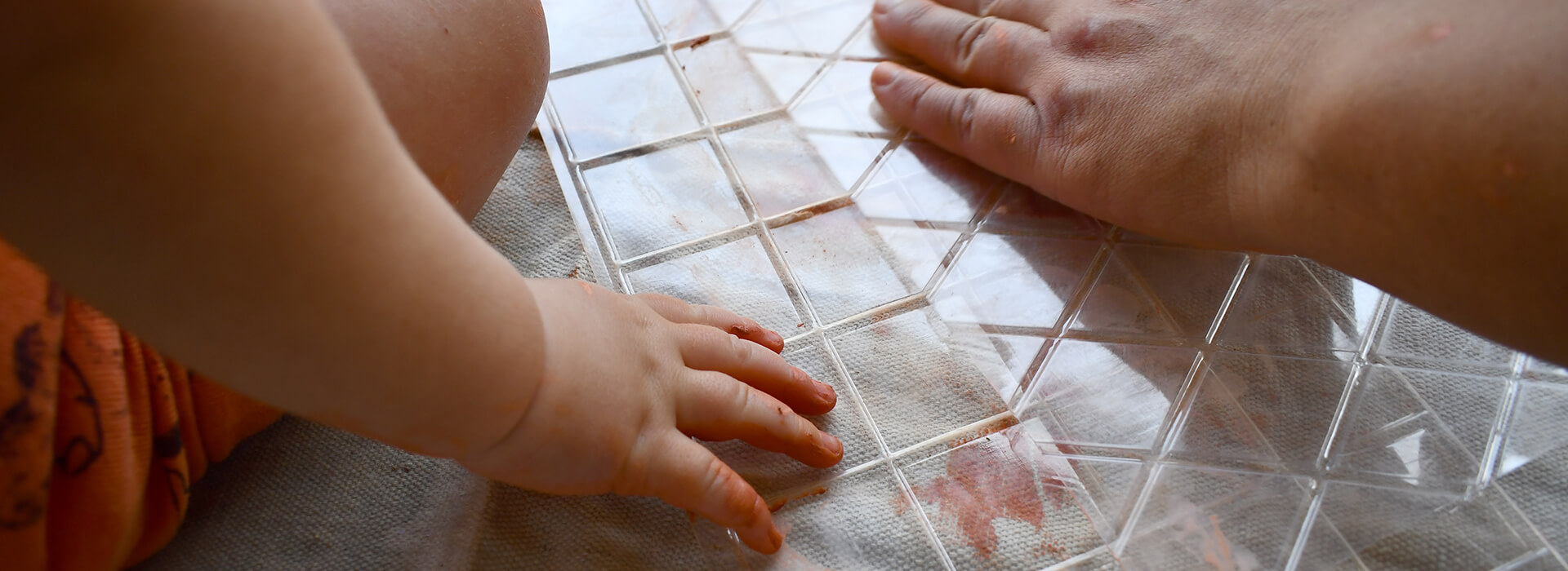 A baby sets its hand down with clay on it