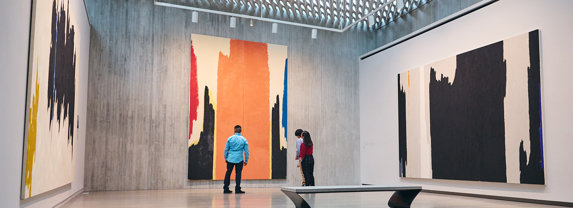 A family stands in a gallery with large, abstract paintings