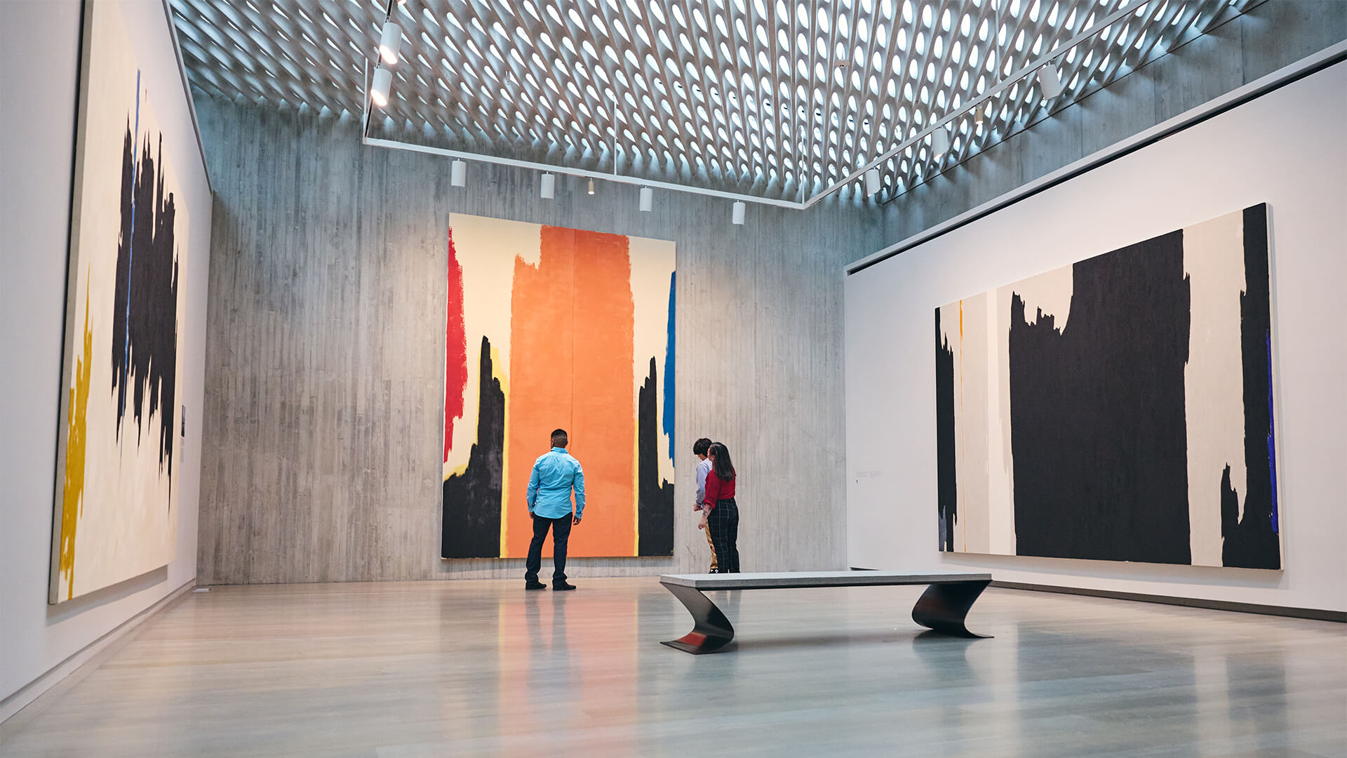 A family stands in a gallery with large, abstract paintings