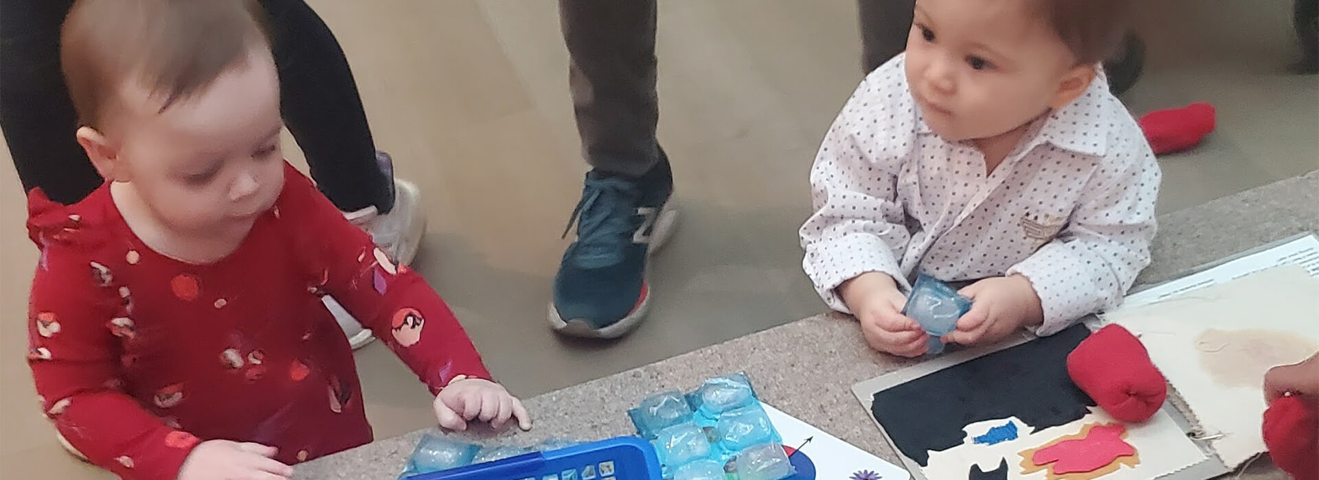 Two babies play with ice cubes and art