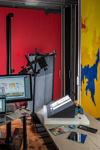 High resolution photographs are taken of an artwork and shown on a screen inside of a painting storage area