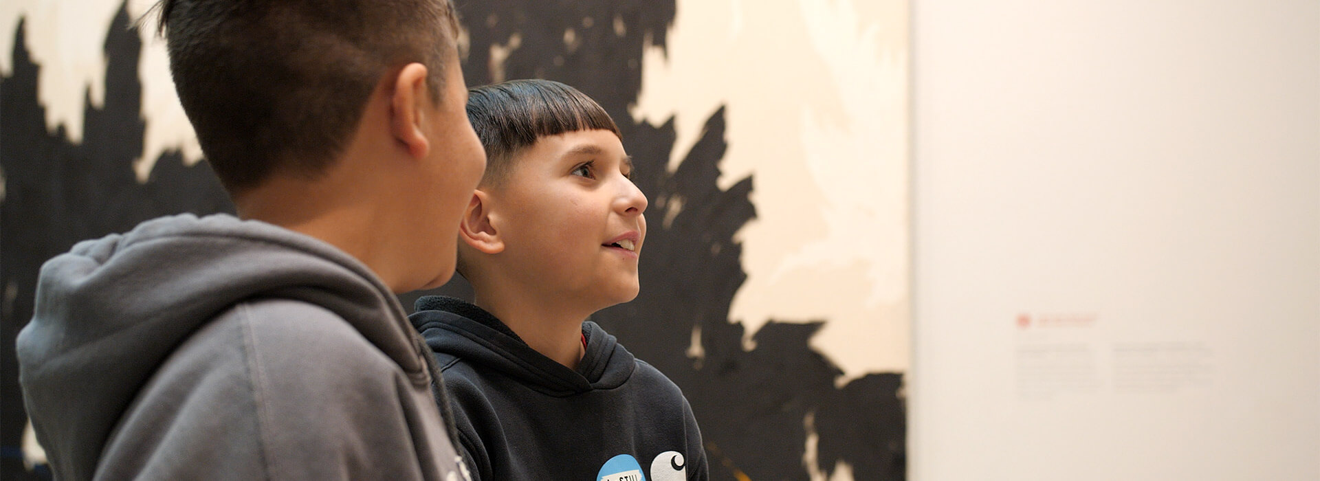 Two students smile and look at a painting