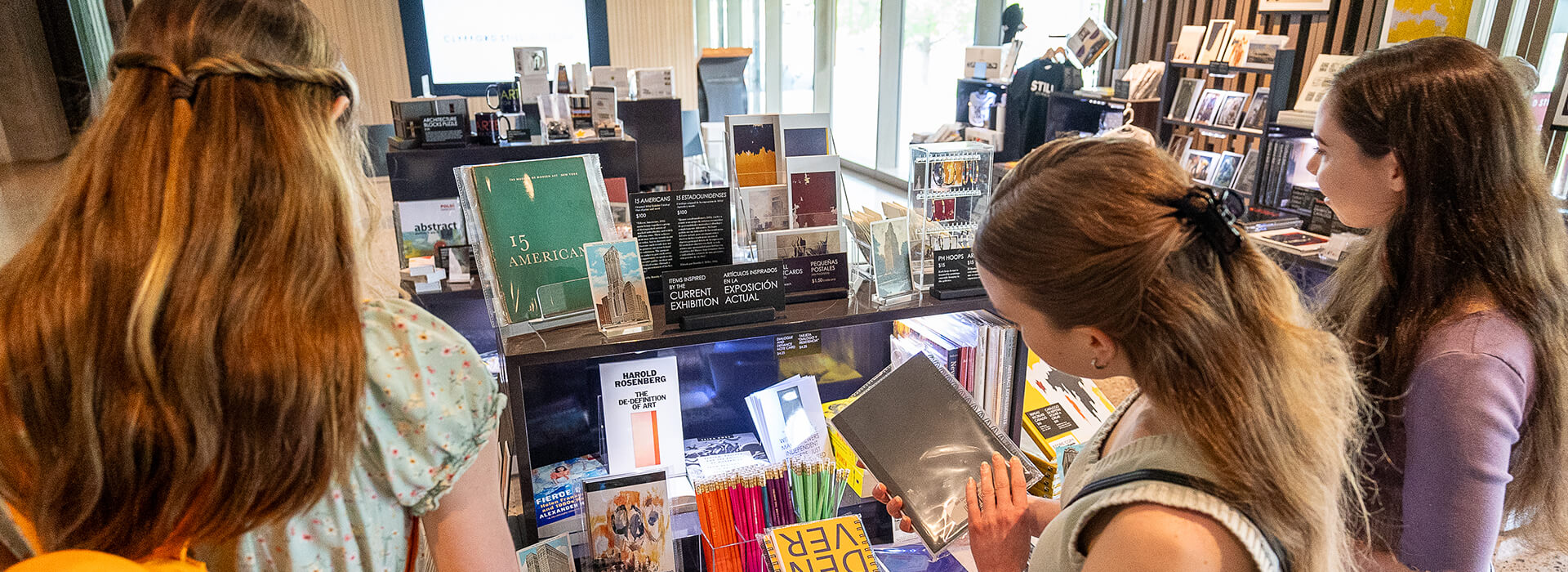 Three young women look at items in a Museum gift shop