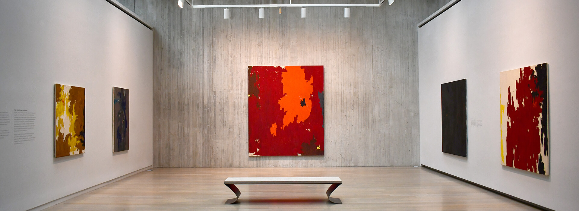 An empty gallery with large, colorful abstract paintings on the walls