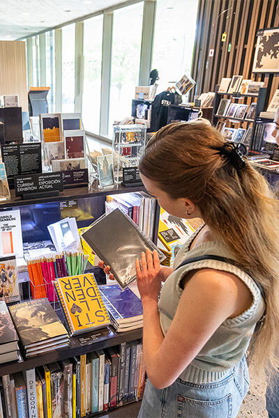 A young woman looks at a book in a museum gift shop