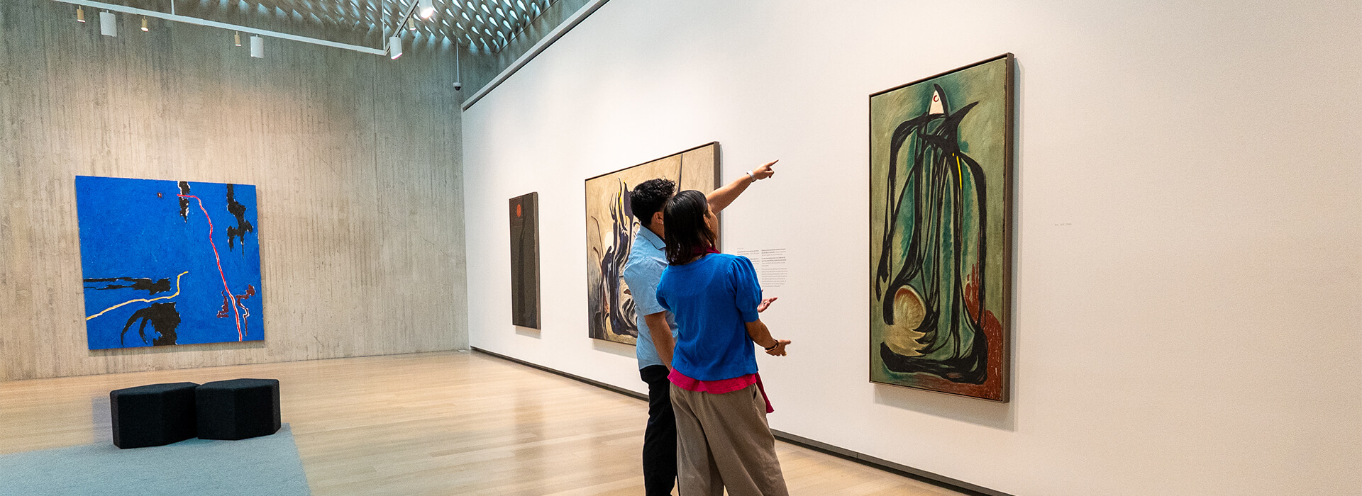 Two people look at a green abstract painting
