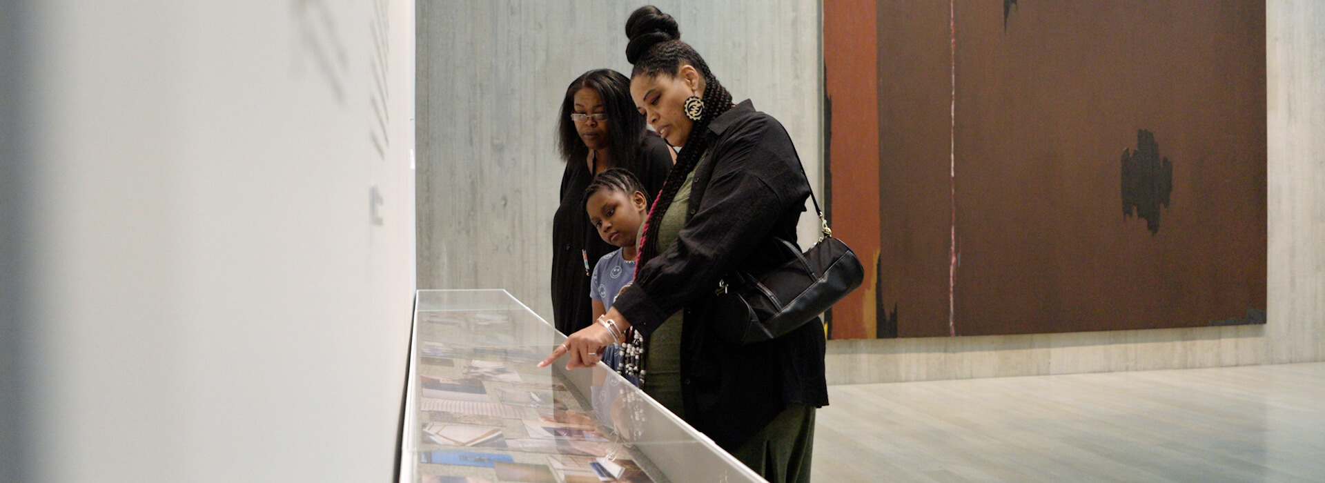 Three people look in a display case