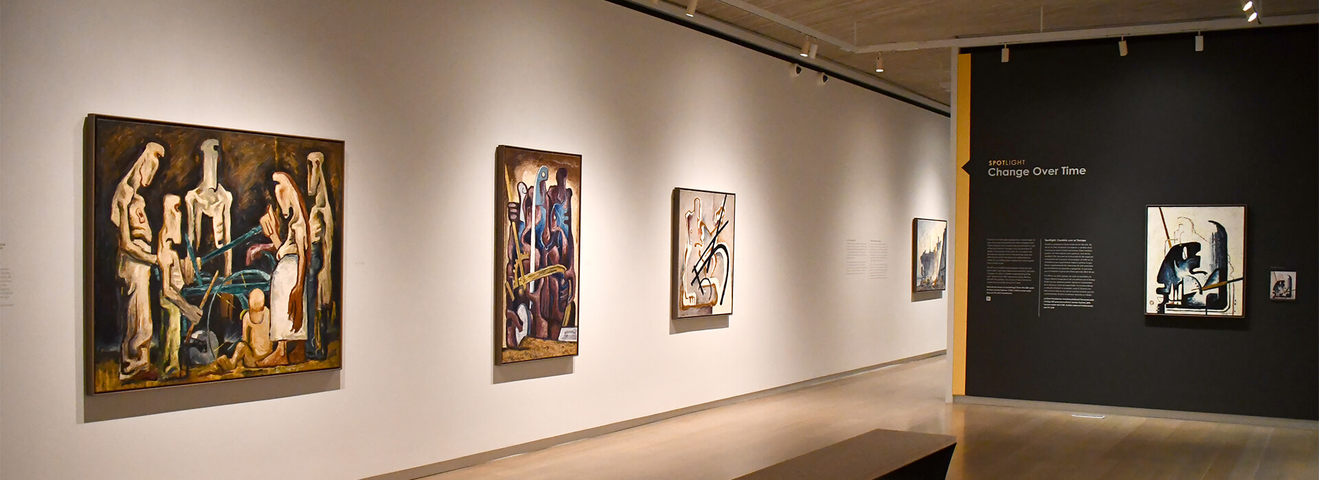Horizontal image of a dark gallery with paintings on the walls