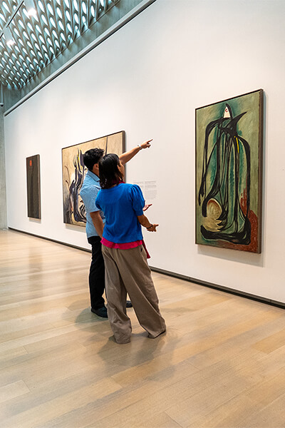 Two people look at a green abstract painting