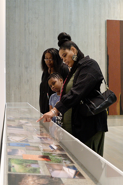 Three people look in a display case