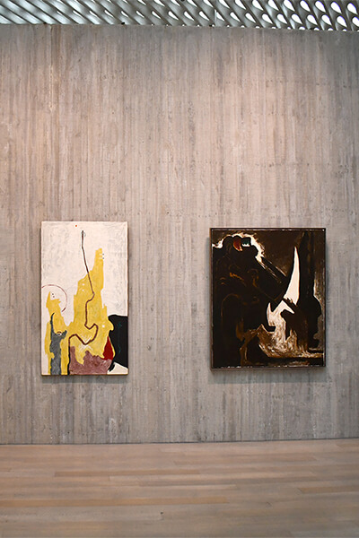 Two abstract paintings with vertical forms hang on a concrete wall in the Clyfford Still Museum