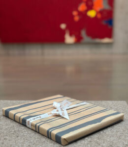 A wrapped package on a bench in front of a painting