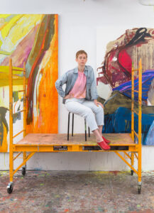 Sarah Faux sitting on a platform in front of large paintings