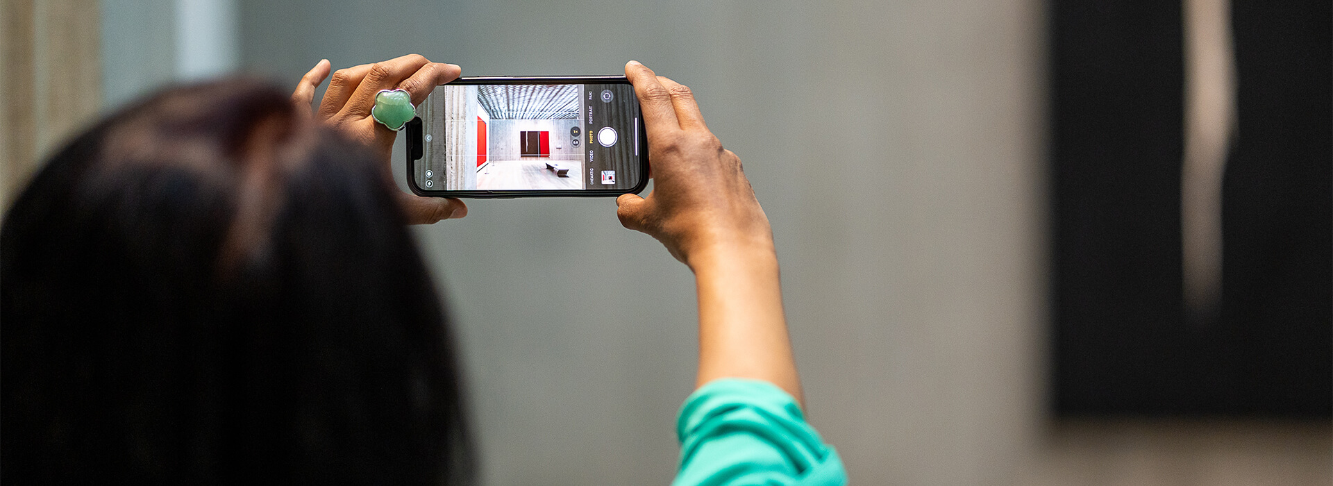 A woman holds a phone up and takes a photo of a gallery