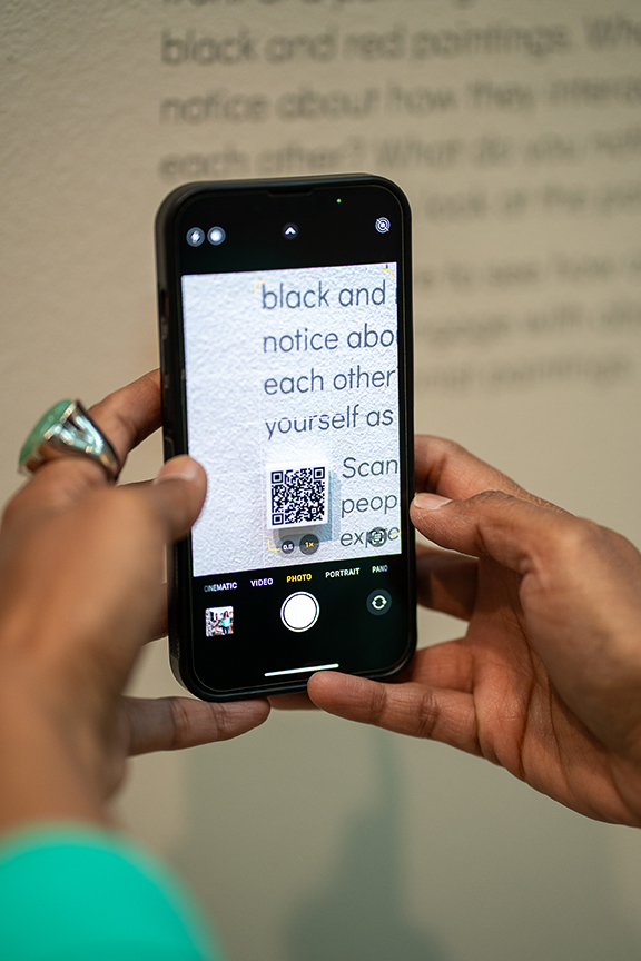 Closeup of a woman's hands holding a phone with a QR code on it