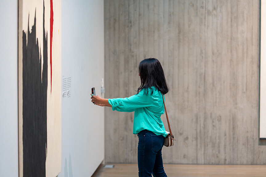 A woman takes a photo of a QR code next to a painting