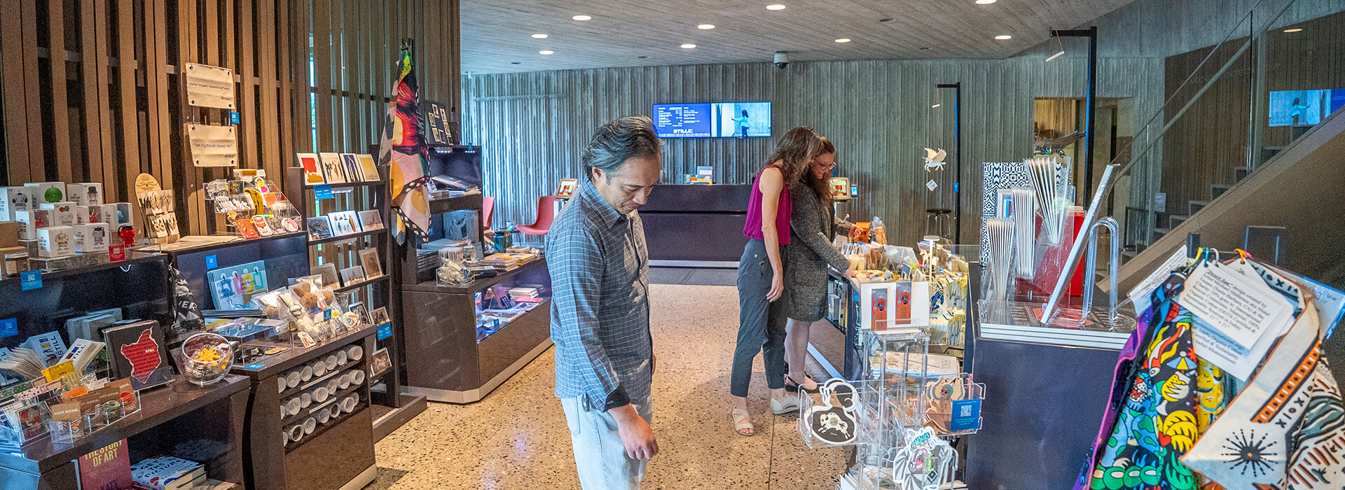 A group of three people look at merchandise in the Clyfford Still Museum Shop