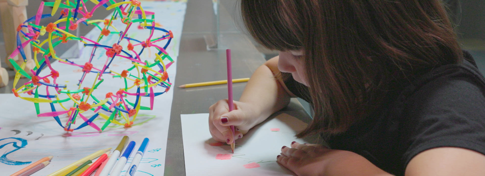 A child draws with a colored pencil