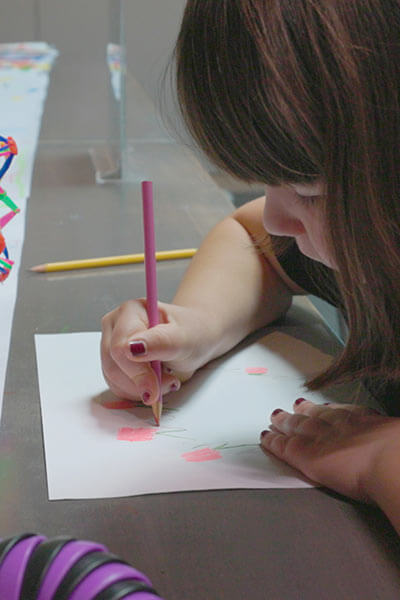A child draws with a colored pencil