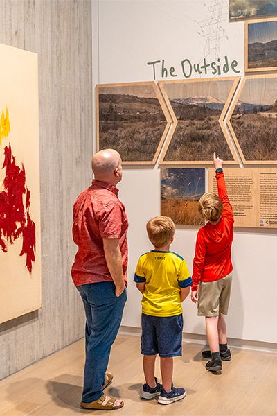 A boy points at a sign that says The Outside