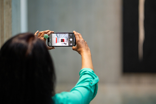 A woman takes a photo of a gallery with her phone