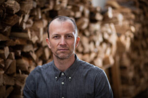 A man stands in front of a wood installation