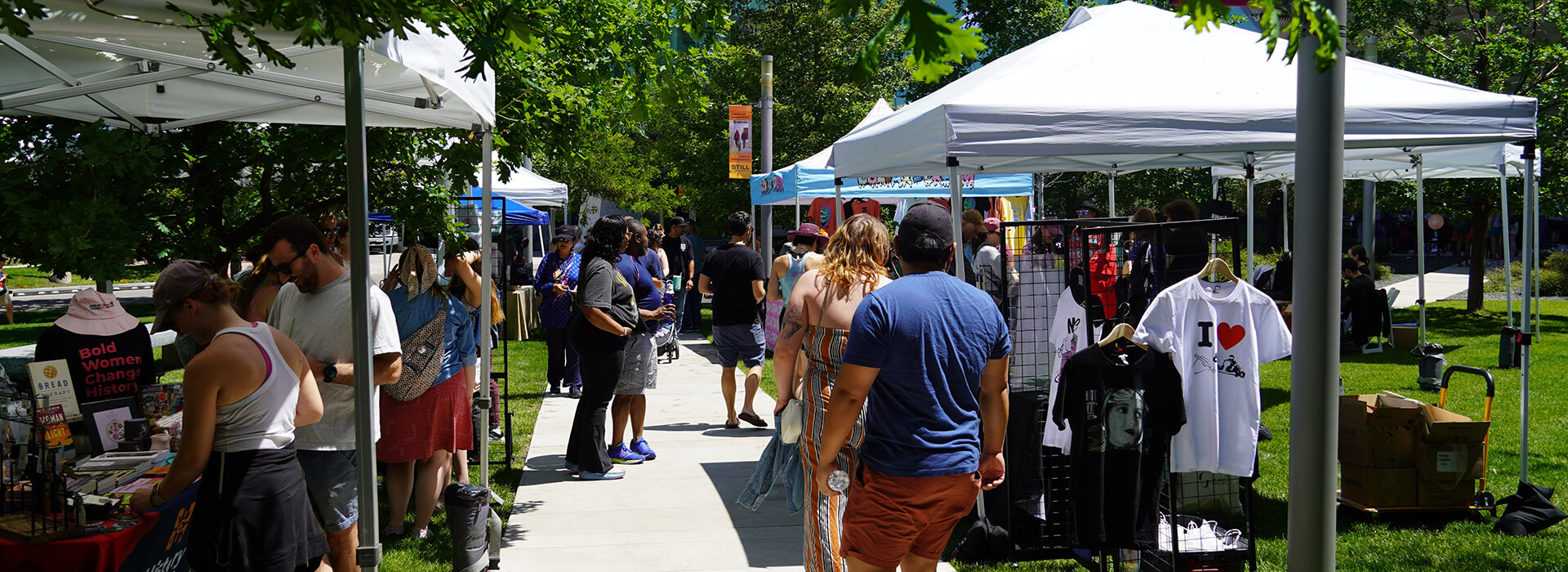 People shop at vendors under tents outside