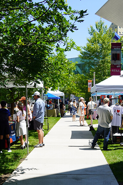 People shop at vendors under tents outside