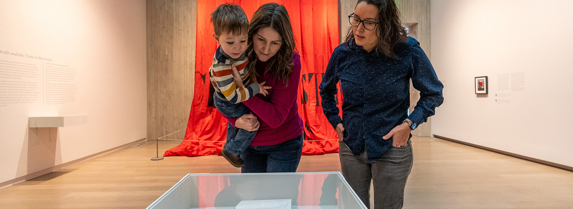 A family leans over and looks into a display case